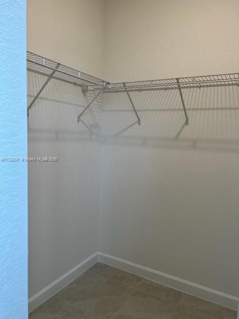 walk in closet featuring dark tile patterned flooring