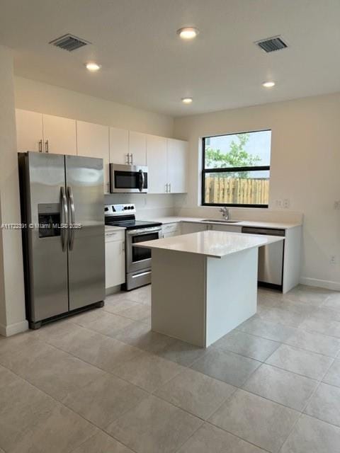 kitchen featuring a kitchen island, white cabinetry, sink, and appliances with stainless steel finishes