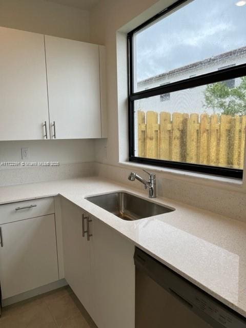 kitchen featuring white cabinetry, sink, light tile patterned floors, and stainless steel dishwasher