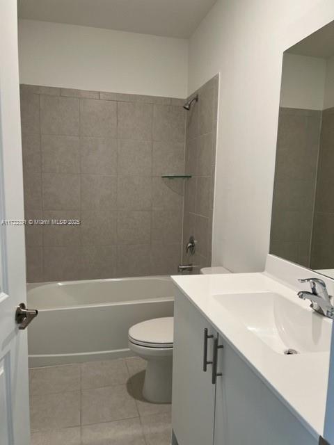 full bathroom featuring tile patterned flooring, toilet, vanity, and tiled shower / bath