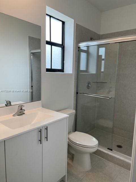 bathroom with tile patterned flooring, vanity, toilet, and an enclosed shower