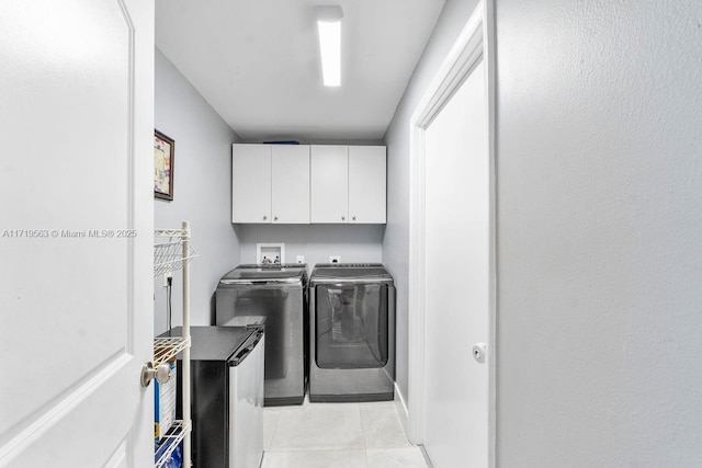 laundry room with washer and clothes dryer, light tile patterned floors, and cabinets