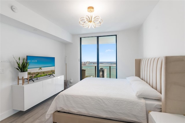 bedroom with light hardwood / wood-style floors, floor to ceiling windows, access to outside, and an inviting chandelier