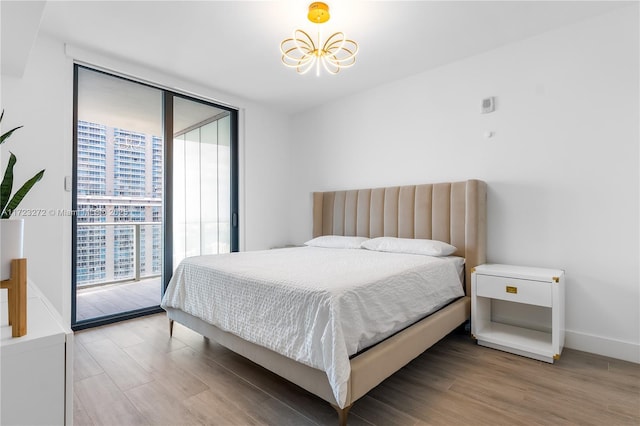 bedroom featuring access to exterior, a wall of windows, wood-type flooring, and multiple windows