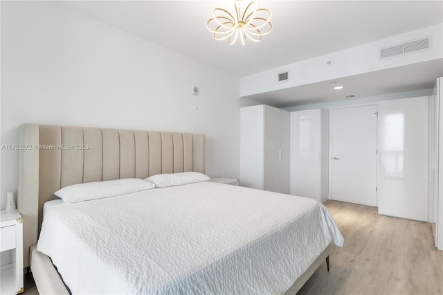 bedroom with light hardwood / wood-style floors and an inviting chandelier