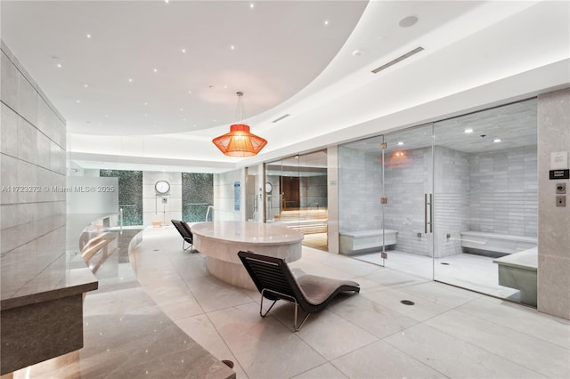 interior space featuring a raised ceiling, tile walls, and a tub