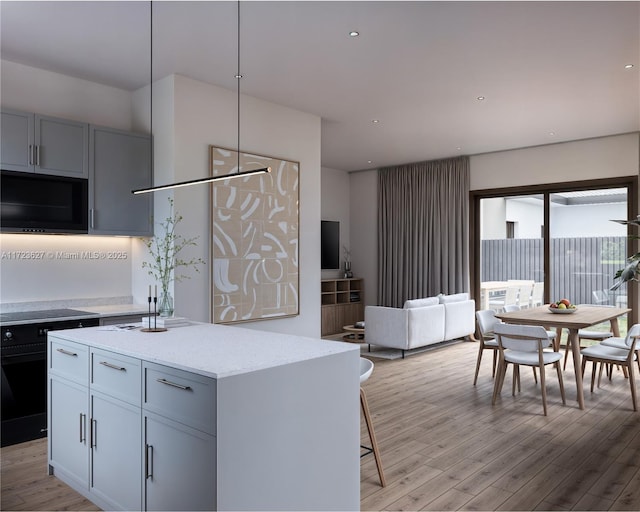 kitchen featuring a kitchen breakfast bar, a center island, range, light stone counters, and light hardwood / wood-style floors