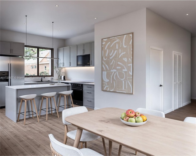 kitchen featuring stainless steel refrigerator with ice dispenser, sink, gray cabinetry, and oven