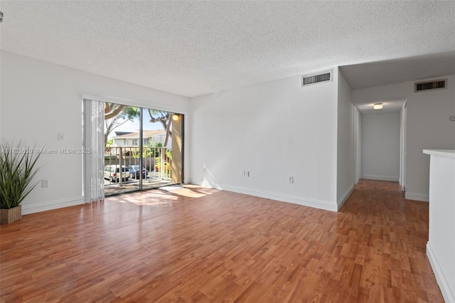 spare room with a textured ceiling and wood-type flooring