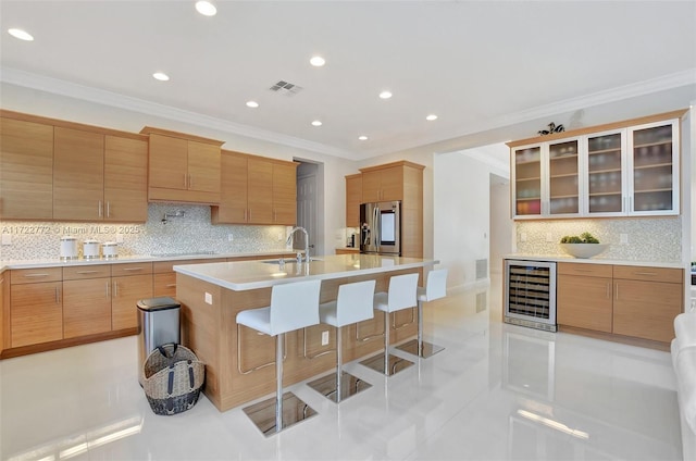 kitchen with a breakfast bar, beverage cooler, a kitchen island with sink, sink, and stainless steel fridge with ice dispenser