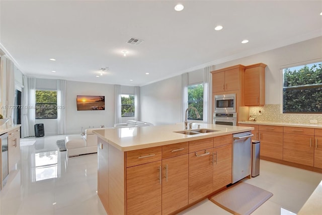 kitchen featuring backsplash, a center island with sink, crown molding, sink, and appliances with stainless steel finishes