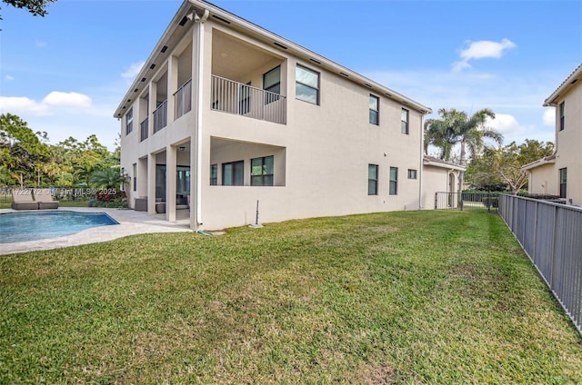 back of house with a fenced in pool, a patio area, and a yard