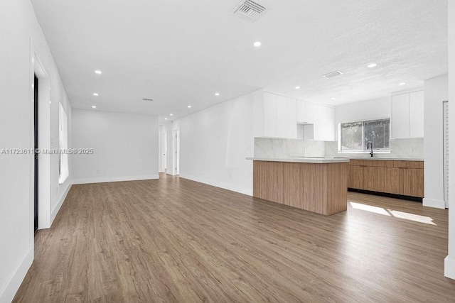 unfurnished living room with light hardwood / wood-style floors and sink