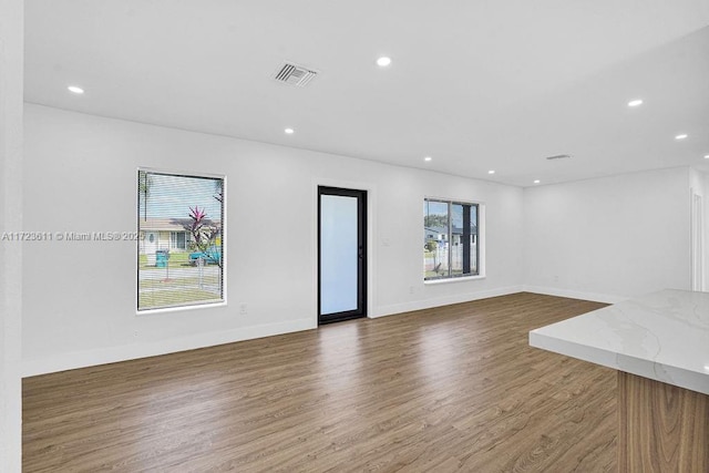 unfurnished living room featuring a healthy amount of sunlight and dark hardwood / wood-style flooring