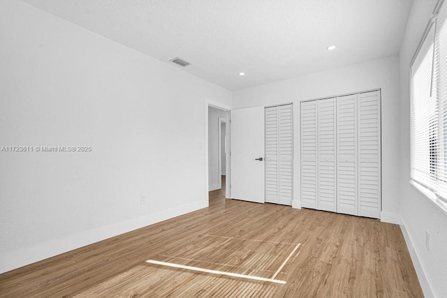 unfurnished bedroom featuring two closets and light hardwood / wood-style flooring