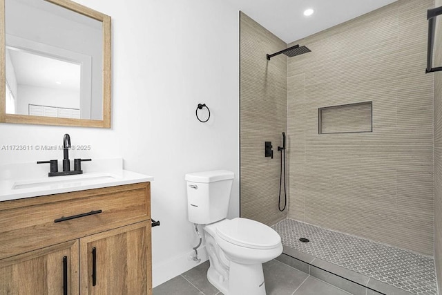 bathroom with tile patterned floors, vanity, tiled shower, and toilet