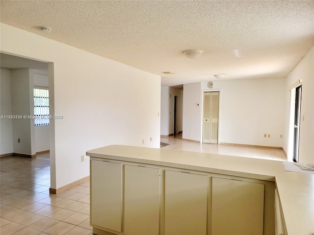 kitchen with light countertops, cream cabinetry, light tile patterned floors, and a textured ceiling