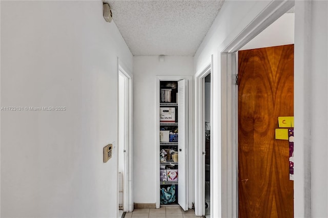 corridor featuring light tile patterned floors and a textured ceiling