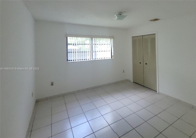 unfurnished room featuring baseboards and light tile patterned flooring