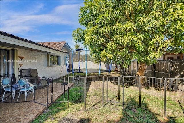 view of yard with a trampoline, a fenced backyard, and a patio area