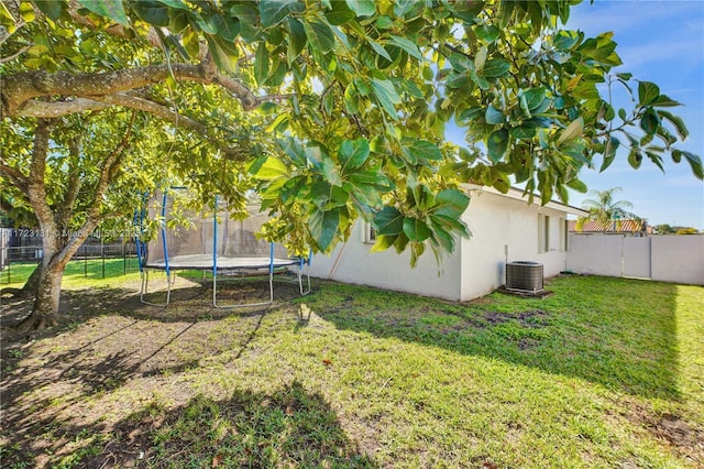 view of yard with a trampoline, a fenced backyard, and central AC