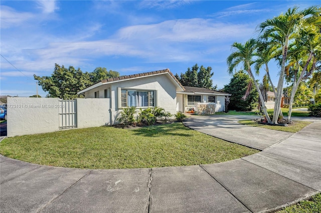 ranch-style home featuring stucco siding, fence, a tiled roof, a front yard, and a gate