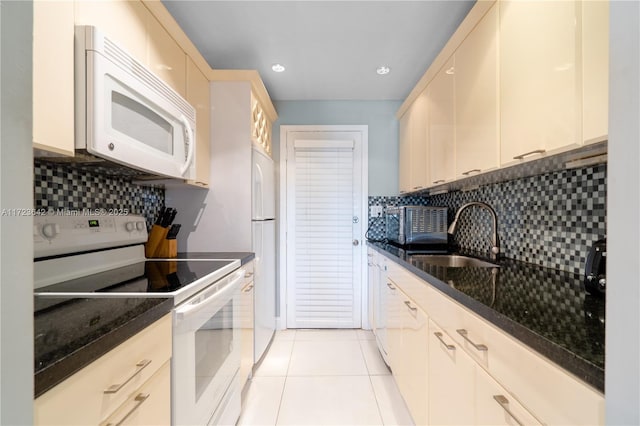 kitchen featuring light tile patterned flooring, white appliances, decorative backsplash, and a sink
