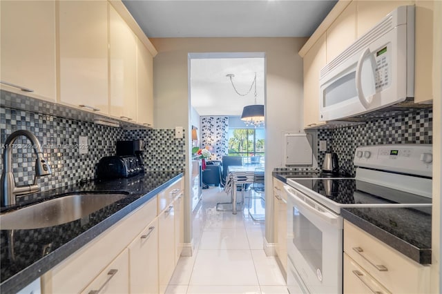 kitchen featuring dark stone countertops, light tile patterned floors, a sink, white appliances, and backsplash