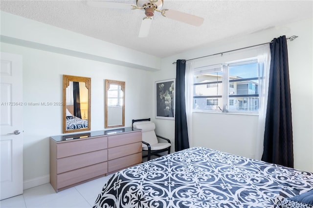 bedroom with baseboards, light tile patterned floors, ceiling fan, and a textured ceiling
