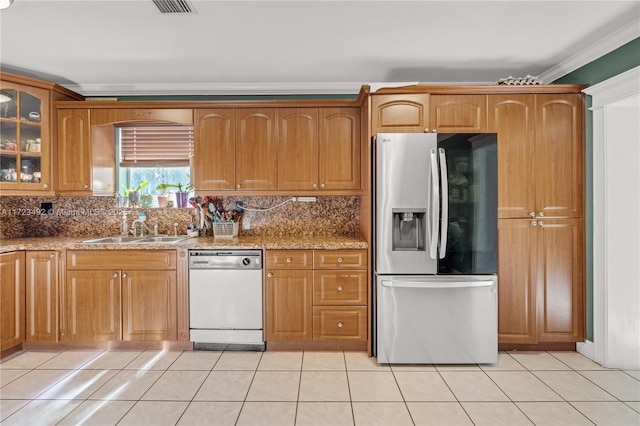 kitchen featuring light stone countertops, stainless steel refrigerator with ice dispenser, white dishwasher, and tasteful backsplash