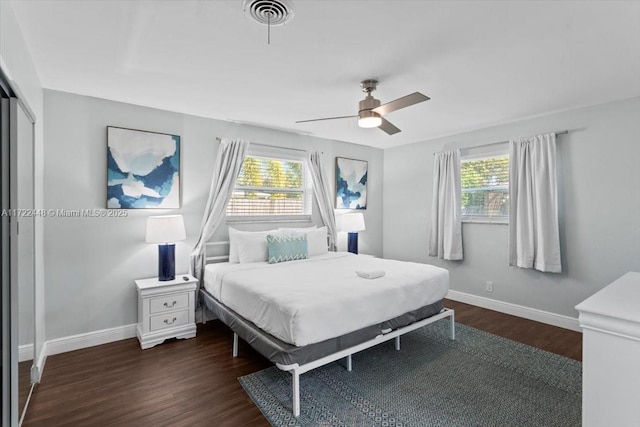 bedroom with multiple windows, dark wood-type flooring, and ceiling fan