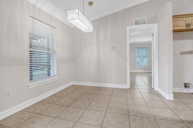 tiled spare room featuring a notable chandelier