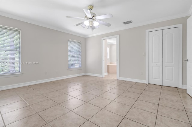 unfurnished bedroom with ensuite bath, ceiling fan, a closet, light tile patterned floors, and ornamental molding