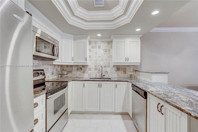 kitchen with crown molding, a tray ceiling, light stone counters, white cabinetry, and stainless steel appliances