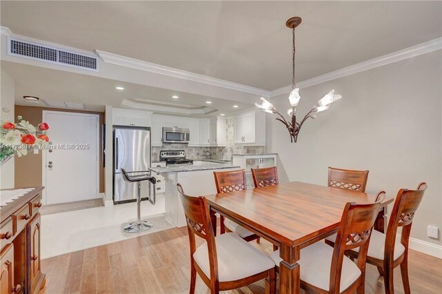 dining area featuring light hardwood / wood-style floors, an inviting chandelier, ornamental molding, and sink