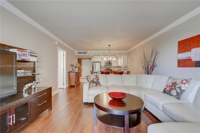 living room featuring a notable chandelier, light wood-type flooring, and crown molding