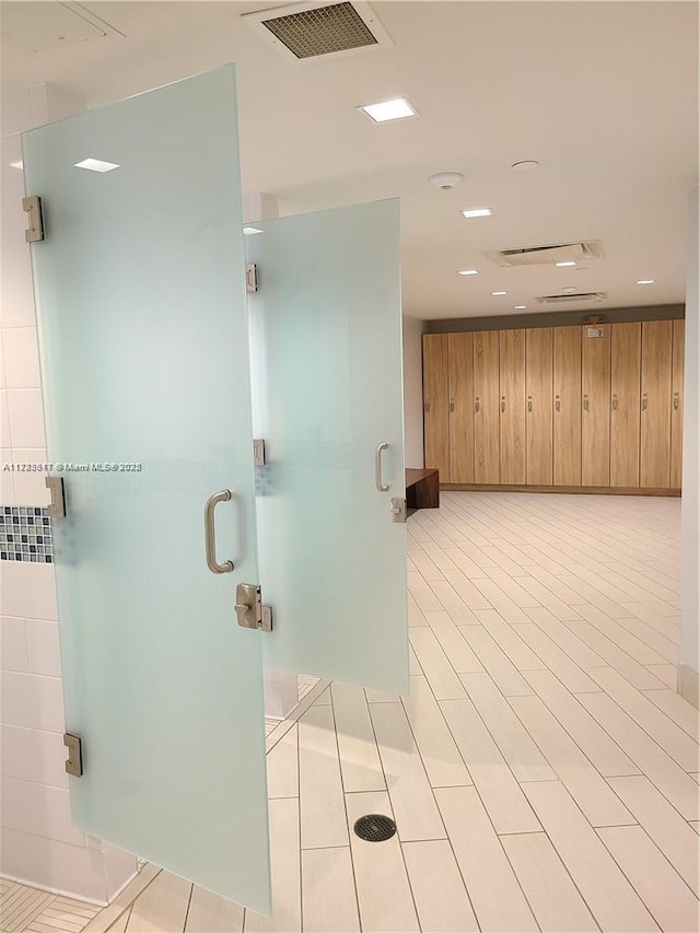 bathroom featuring wooden walls and a shower with door