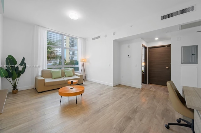 living room with light wood-type flooring, electric panel, and a wall of windows