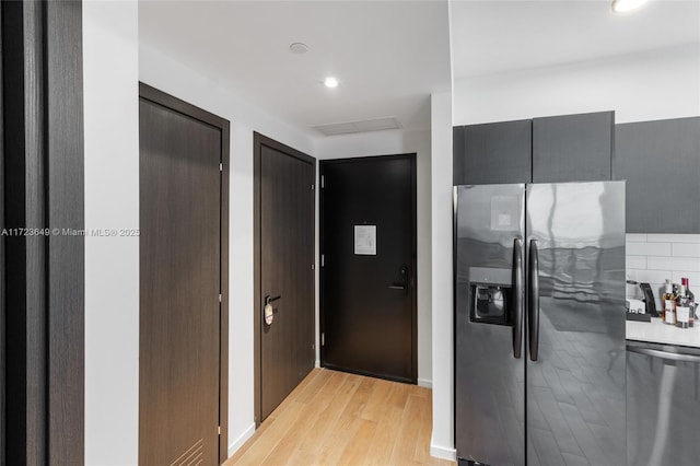 kitchen with decorative backsplash, light wood-type flooring, and appliances with stainless steel finishes