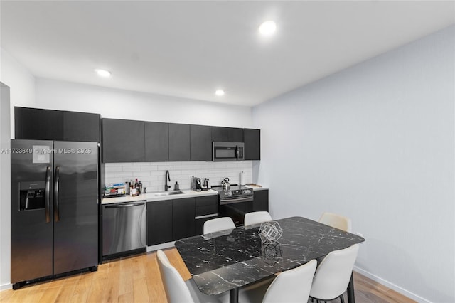 kitchen featuring light wood-type flooring, stainless steel appliances, tasteful backsplash, and sink