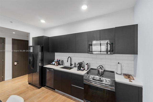 kitchen featuring decorative backsplash, stainless steel appliances, light hardwood / wood-style flooring, and sink