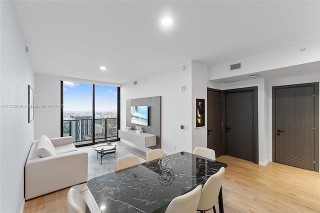 dining space with floor to ceiling windows and light hardwood / wood-style flooring