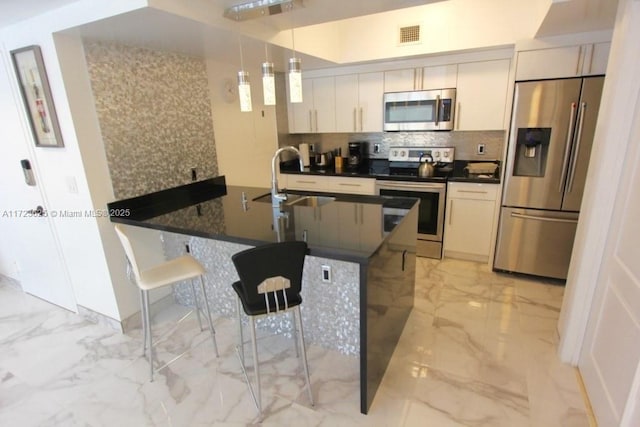 kitchen featuring sink, a kitchen breakfast bar, backsplash, pendant lighting, and appliances with stainless steel finishes