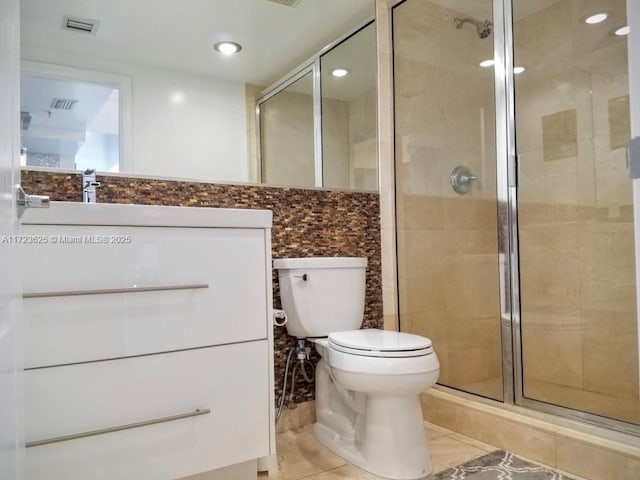 bathroom featuring tasteful backsplash, tile patterned floors, toilet, vanity, and a shower with shower door