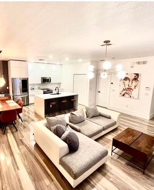 living room featuring sink, a textured ceiling, and light wood-type flooring