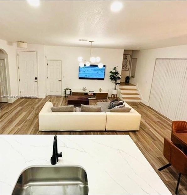 living room with light hardwood / wood-style floors, an inviting chandelier, and sink