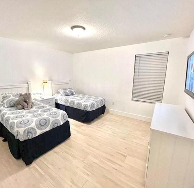 bedroom with light hardwood / wood-style floors and a textured ceiling