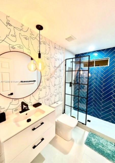 bathroom featuring tile patterned flooring, vanity, toilet, and an enclosed shower