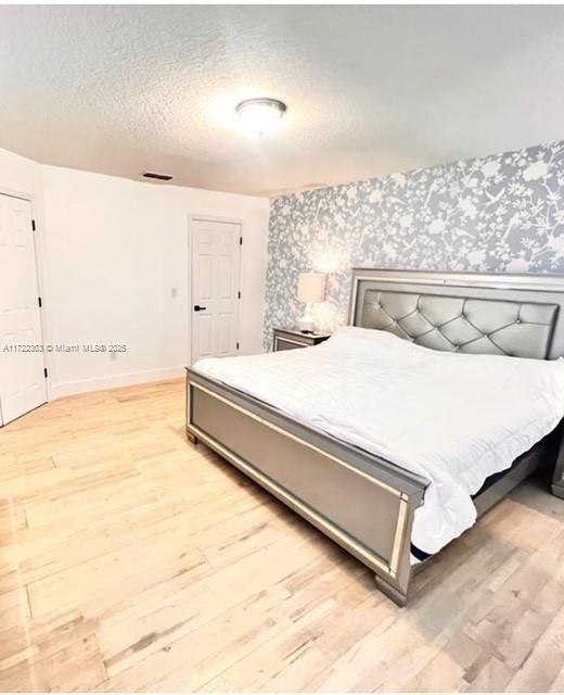 bedroom featuring a textured ceiling and light hardwood / wood-style flooring