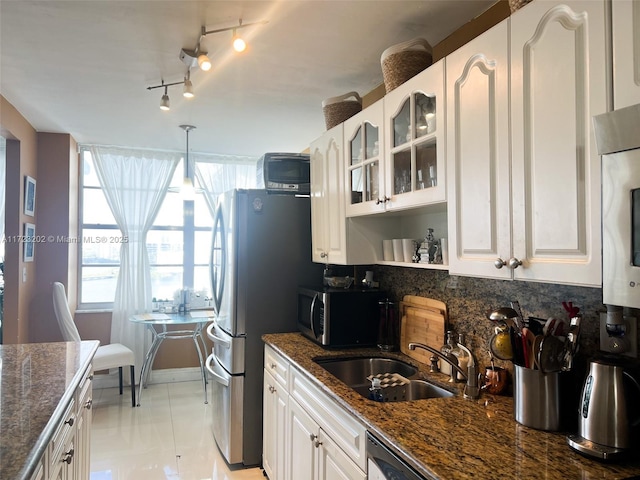 kitchen featuring stainless steel appliances, sink, pendant lighting, dark stone countertops, and white cabinetry